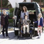 A scene from ABC's new series, Speechless: A lift lowering Minnie Driver and Micah Fowler from the open doors at the back of an accessible van. They are both showing a lot of attitude. They are flanked by the father and sister of the family.