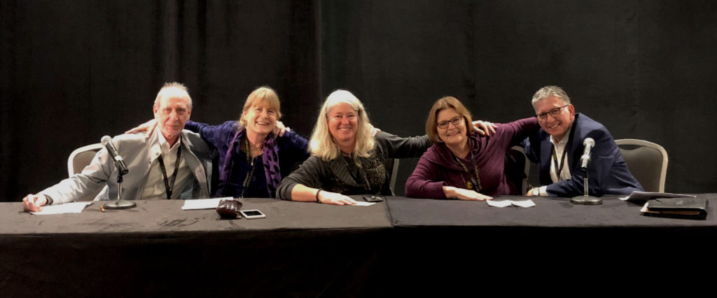 A photograph of the WIOA advisory panel. It is after the panel and the four are posing, leaning together with their arms around one another.