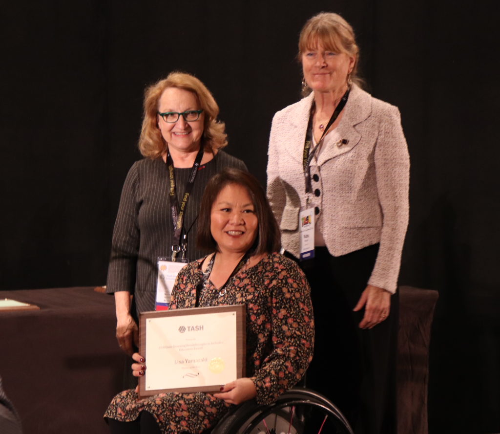 A photograph of Lisa Yamasaki receiving an award from Ruthie Beckwith and Ruby Moore.