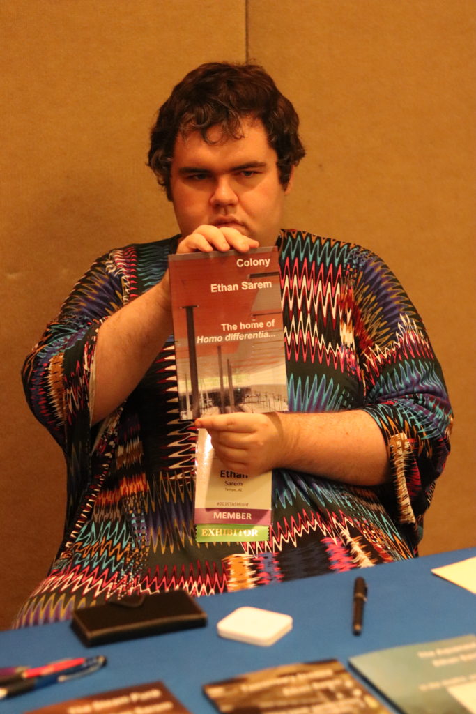 A photograph of the pseudonymous author Ethan Sarem holding up his book, The Home of Homo Differentia