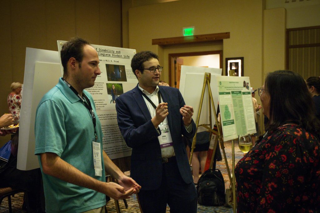 A photograph of Will Fried and Jake Goodman discussing their poster to an attendee.