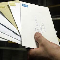 An image of a single hand holding a fanned stack of stamped envelopes