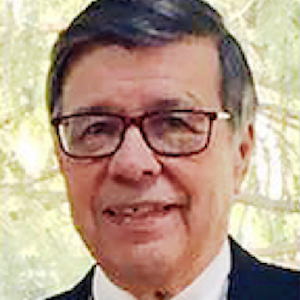 A portrait of Frank Laksi: he has dark grey hair parted at one side, and glasses. He is wearing a suite and tie.